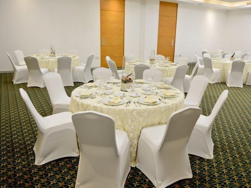 una habitación llena de mesas y sillas con cubiertas blancas