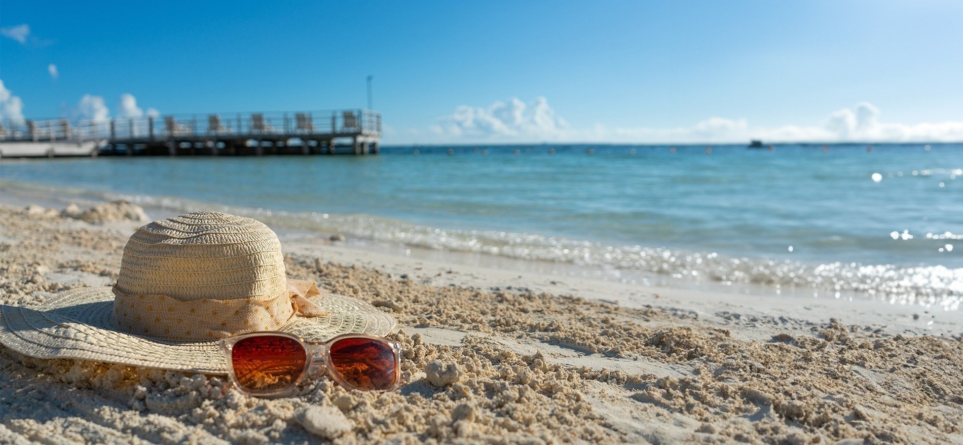a hat and sunglasses are on the beach near the water