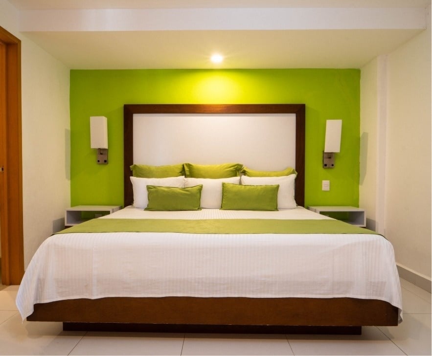 a hotel room with a bed and green walls