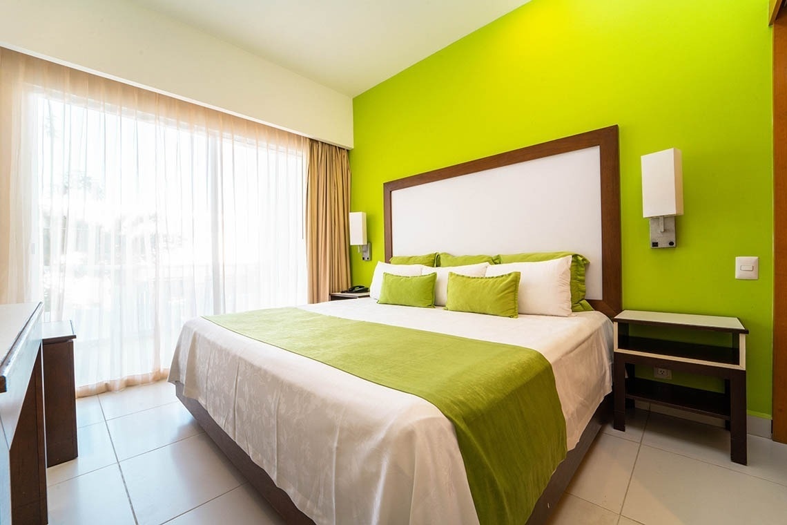 una habitación con paredes verdes y una cama blanca