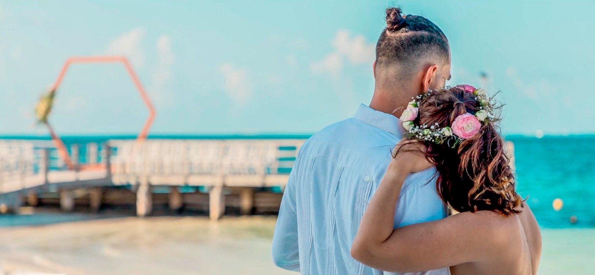 a man and a woman standing on a beach with flowers in their hair