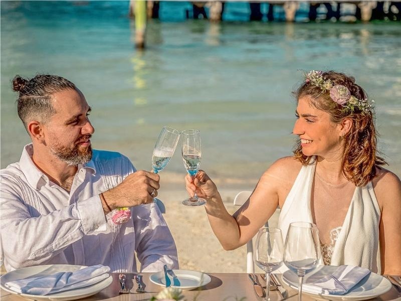 a man and woman toasting with champagne glasses on the beach