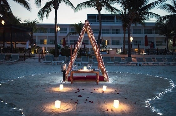 una mesa en la playa está rodeada de velas y rosas