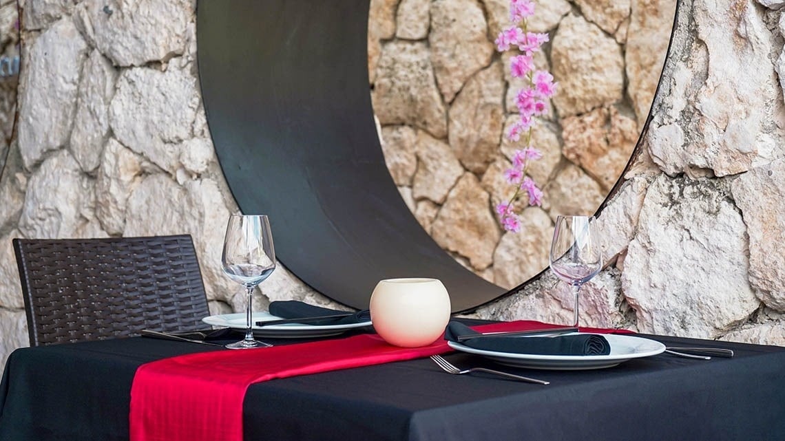 una mesa con platos y copas de vino frente a una pared de piedra