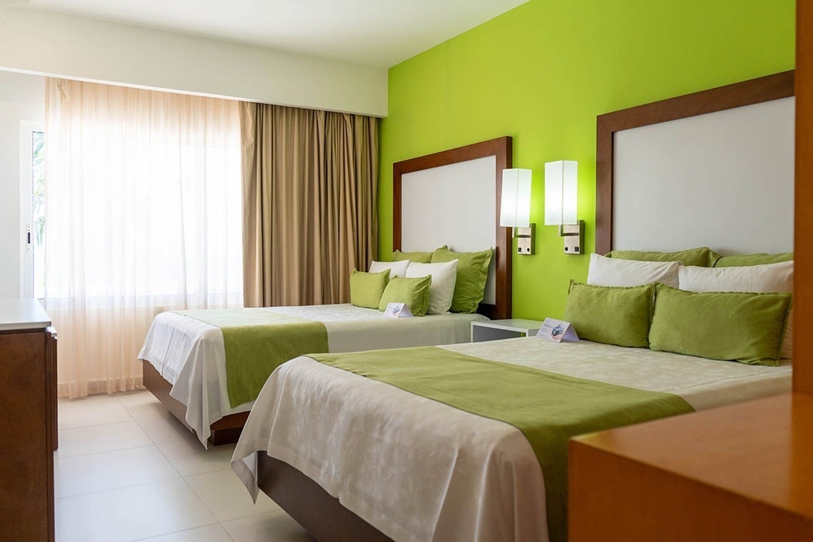 una habitación de hotel con dos camas y una pared verde