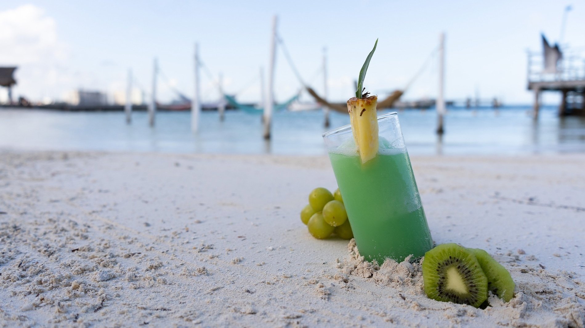 a green drink with kiwi and grapes on the beach