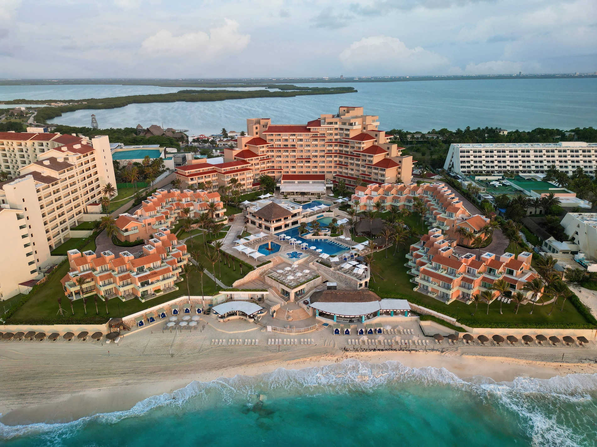 Piscina cristalina Wyndham Grand de Grupo Cancun con palmeras y resort.