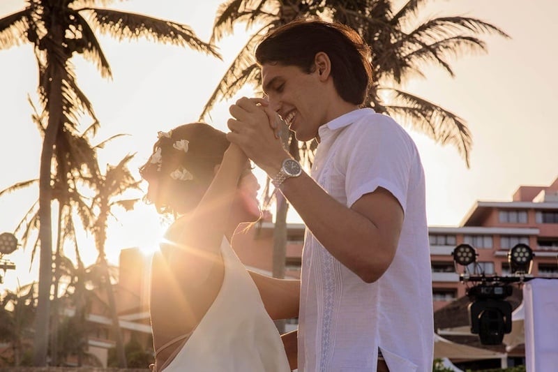 un hombre y una mujer bailan en la playa al atardecer