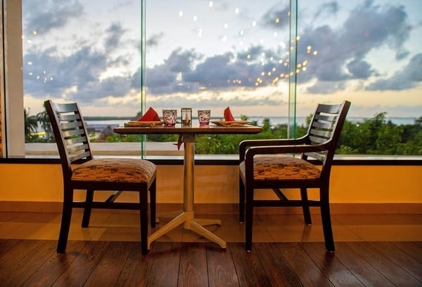 two chairs and a table in front of a window with a view of the ocean