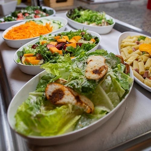 a variety of salads and pasta on a buffet tray