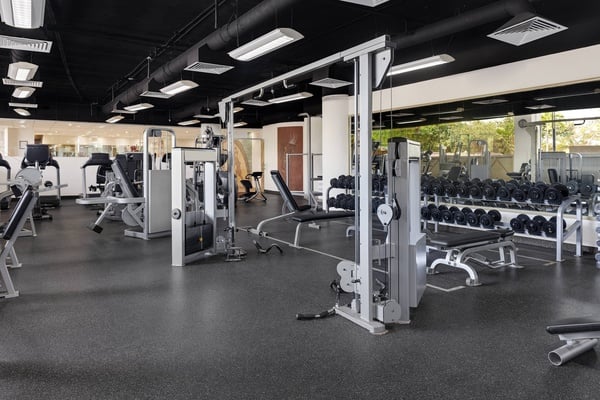 un hombre levanta pesas frente a un espejo en un gimnasio