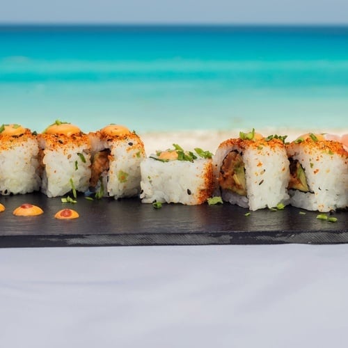 a tray of sushi on a table with the ocean in the background
