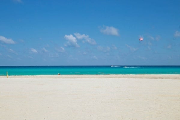 an empty beach with a red parachute in the distance