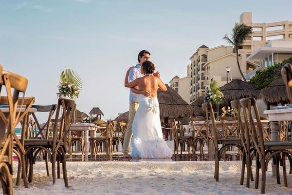 una novia y un novio bailan en la playa