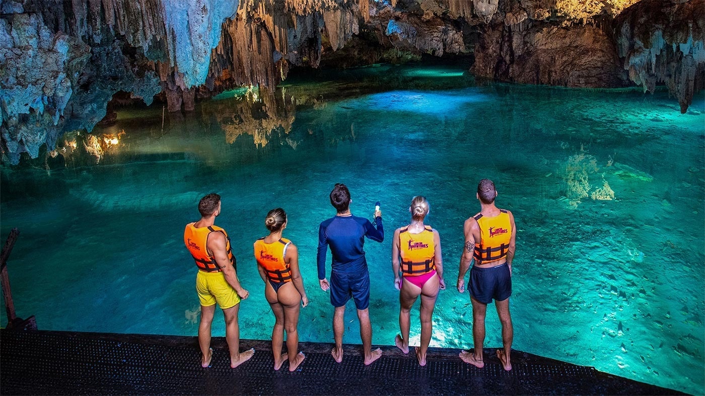 a group of people standing in a cave wearing life jackets