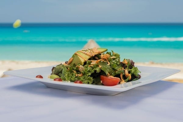 a salad with avocado and tomatoes on a white plate