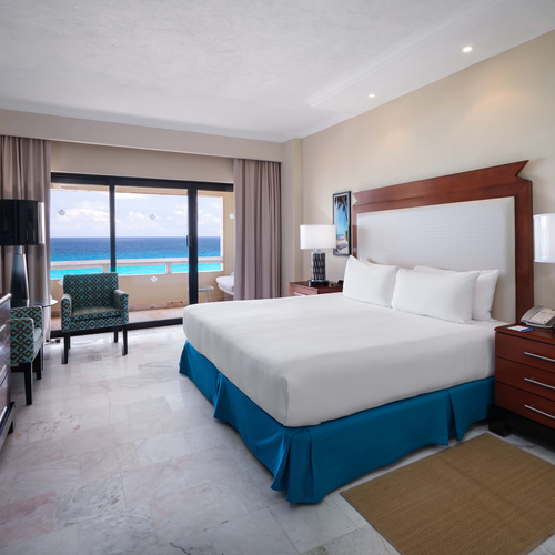 a hotel room with a king size bed , television , dresser and chair .