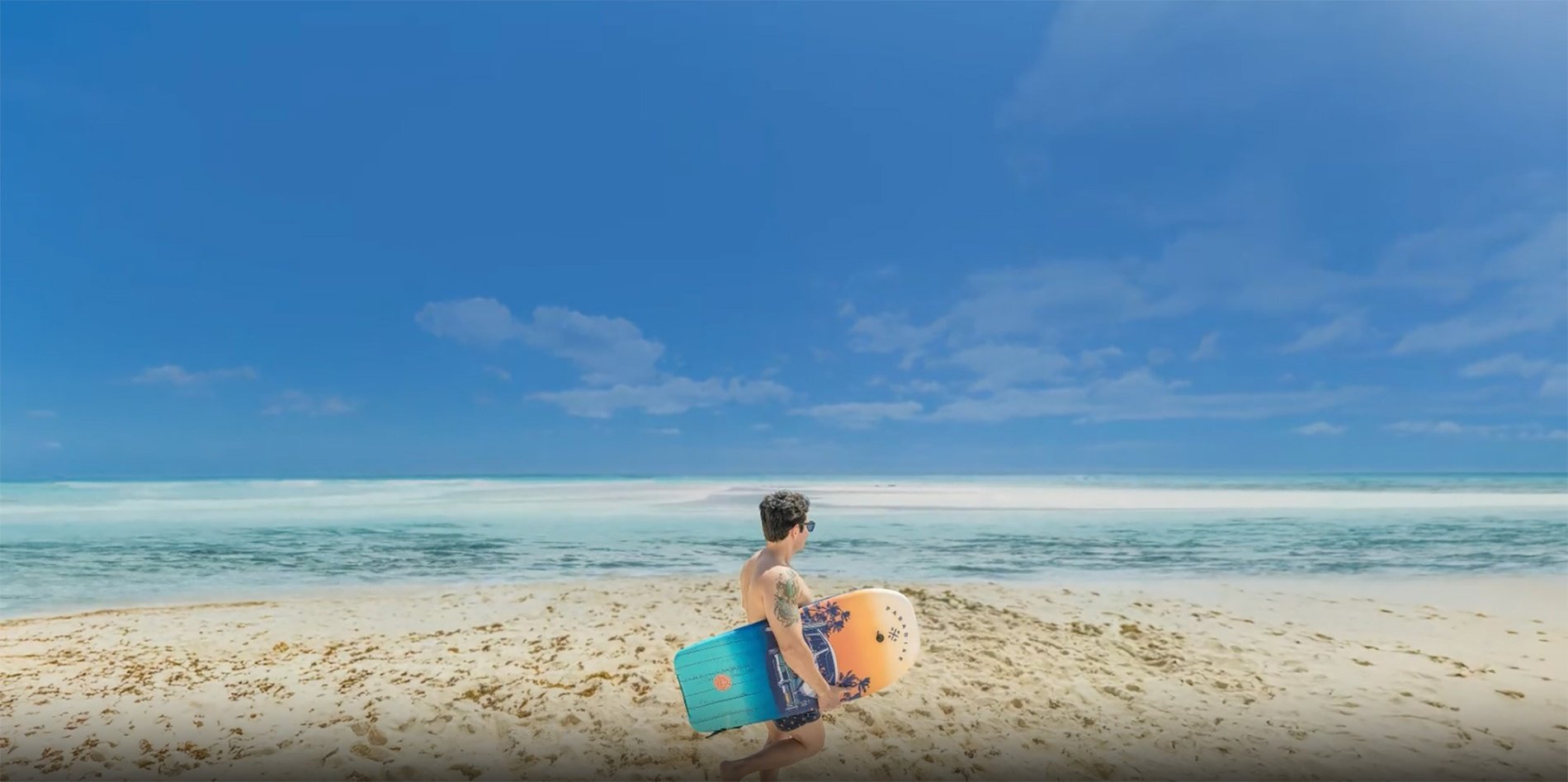 un hombre lleva una tabla de surf en la playa