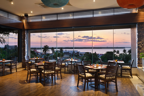 un restaurante con mesas y sillas y una vista del océano al atardecer