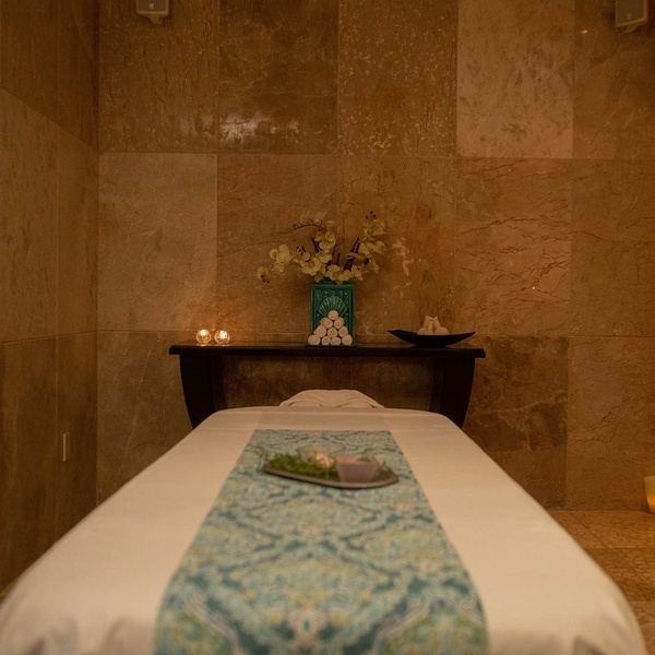 a massage table in a room with a vase of flowers and candles