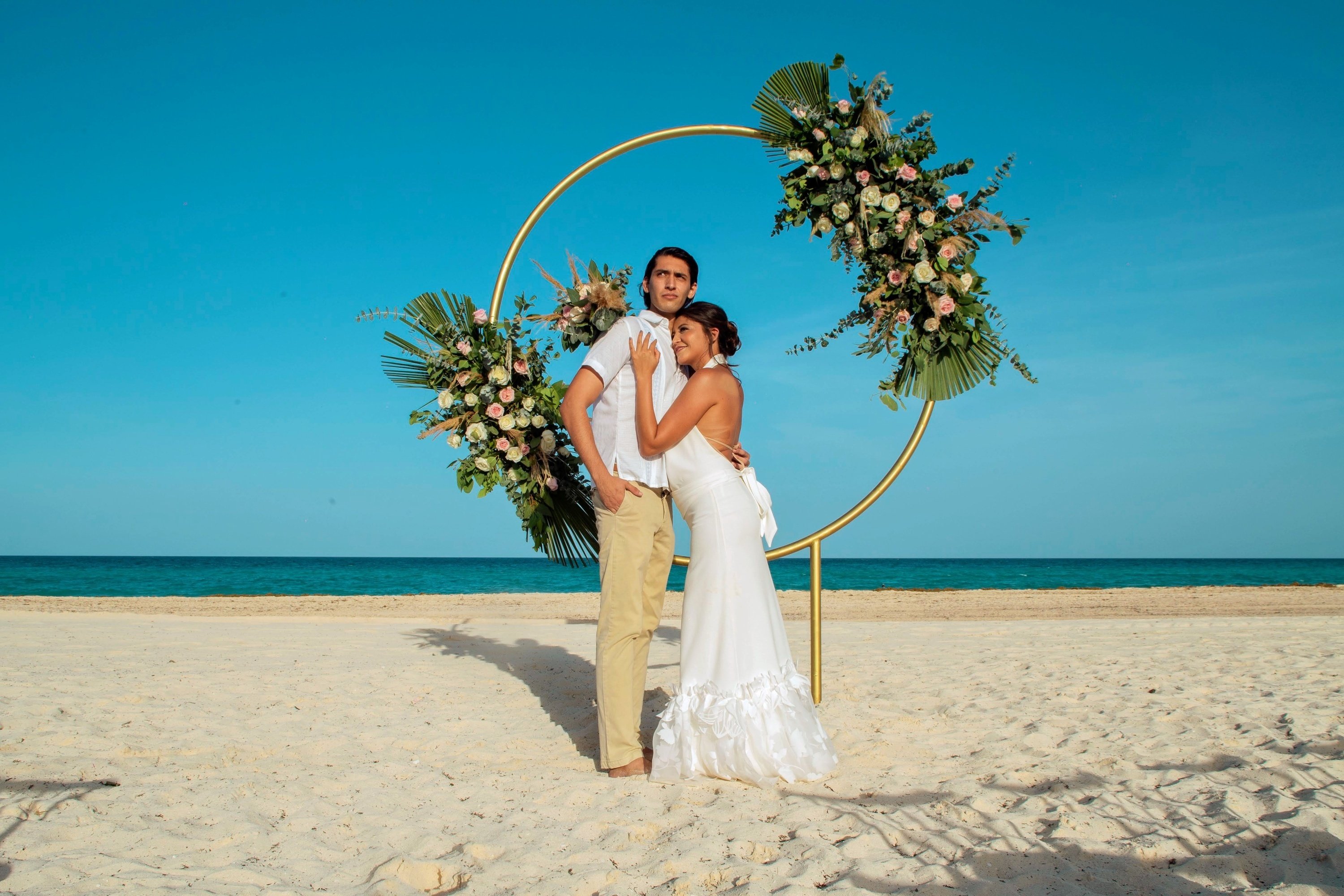 a bride and groom pose for a picture on the beach