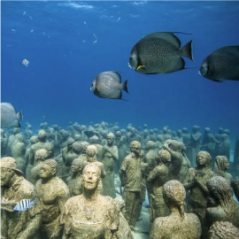 un grupo de estatuas están en el océano rodeadas de peces