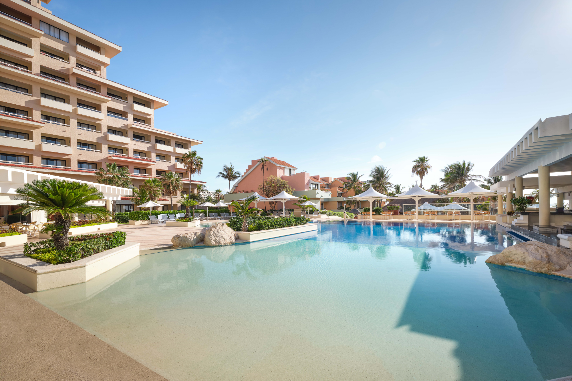 a large swimming pool surrounded by umbrellas and palm trees