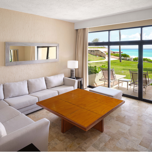 a living room with a couch and a table with a view of the ocean