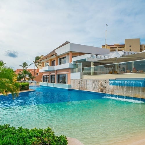 a large swimming pool with a waterfall in front of a building