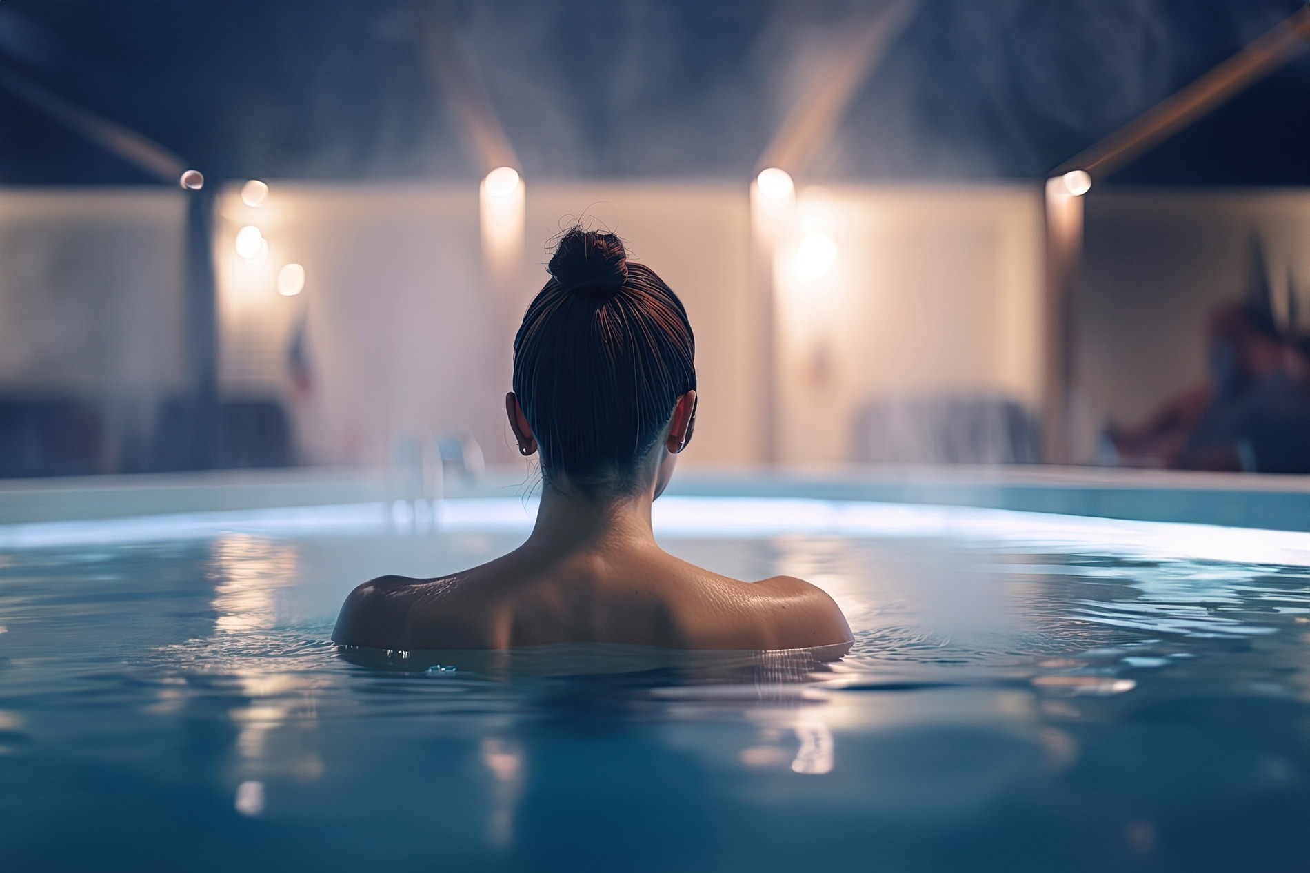 a woman is swimming in a pool at night