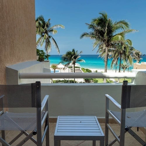 two director 's chairs sit on a balcony overlooking the ocean