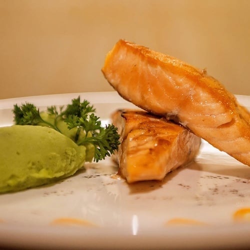a white plate topped with a piece of salmon and mashed potatoes