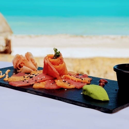 a plate of food on a table with a beach in the background