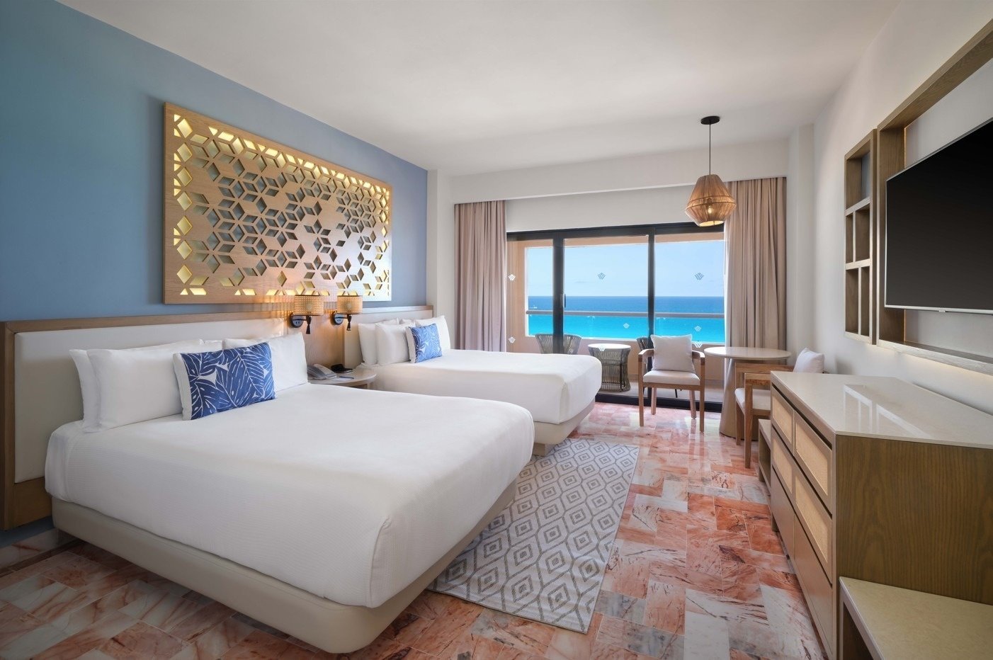 a hotel room with two beds and a balcony overlooking the ocean