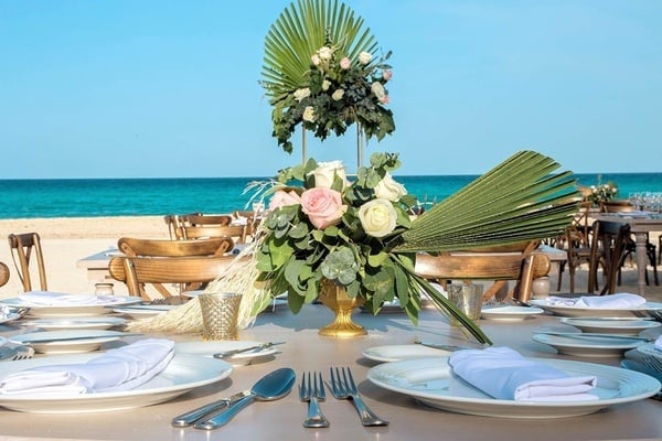 una mesa está decorada para una boda en la playa con platos y cubiertos