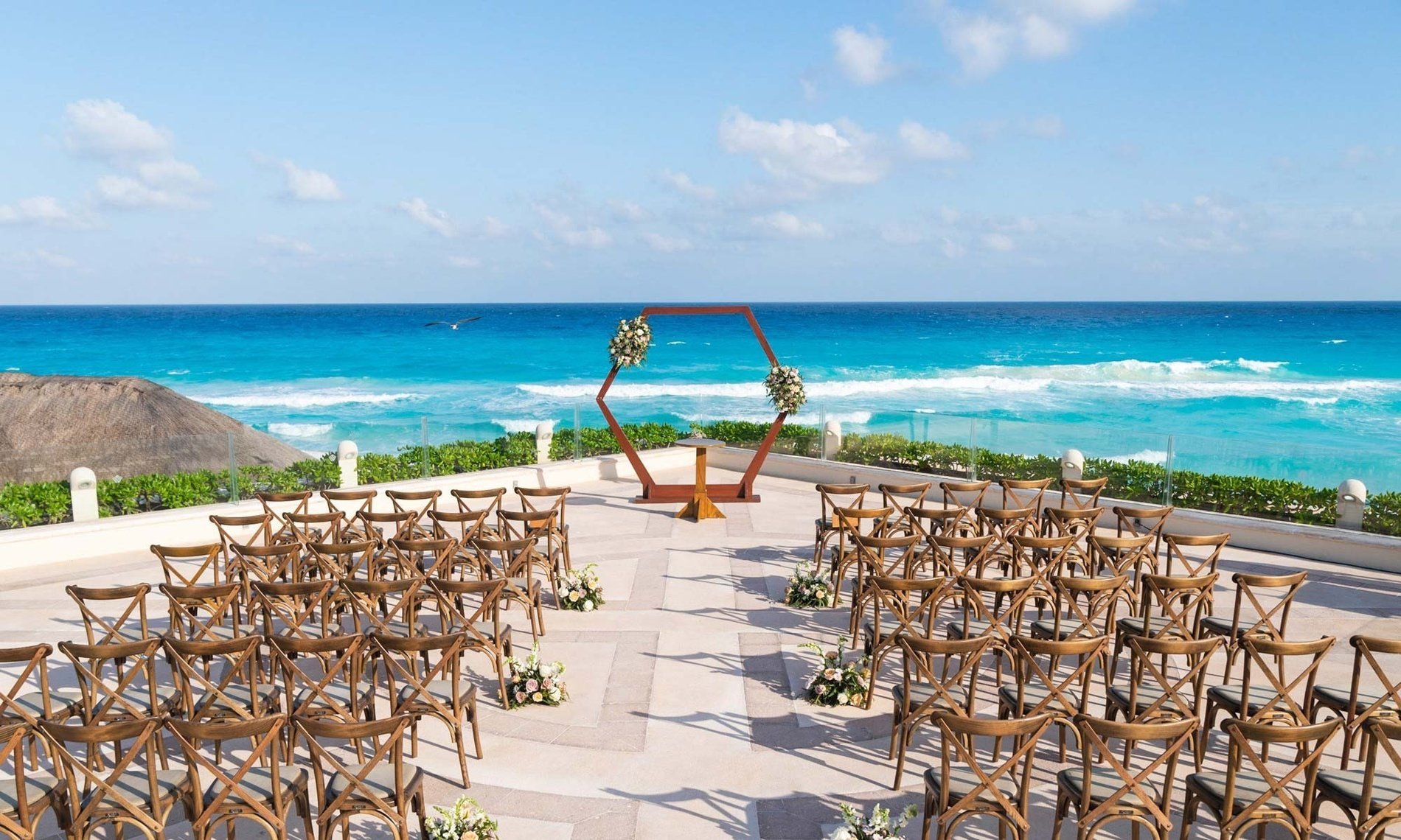 a row of wooden chairs are lined up in front of a wooden arch overlooking the ocean