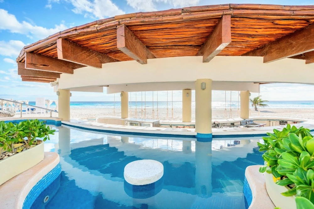 Bar acuático Wyndham Grand Cancún All Inclusive Resort & Villas con vista al mar y palmeras.