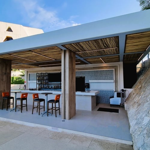 a white building with a bar and stools in front of it