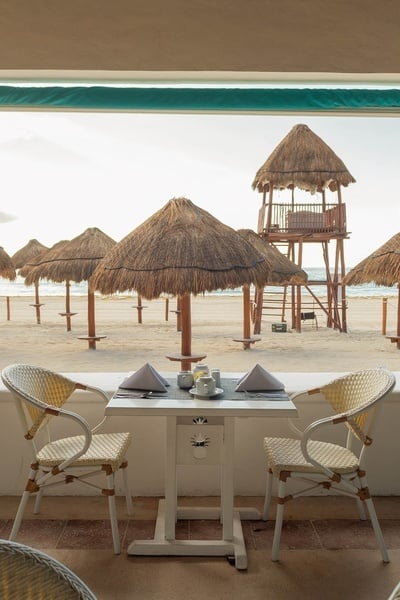 una mesa y sillas en la playa con una torre de salvavidas en el fondo