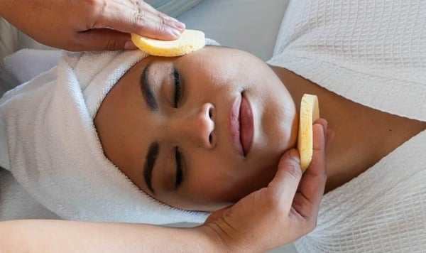 una mujer con una toalla en la cabeza recibe un masaje facial