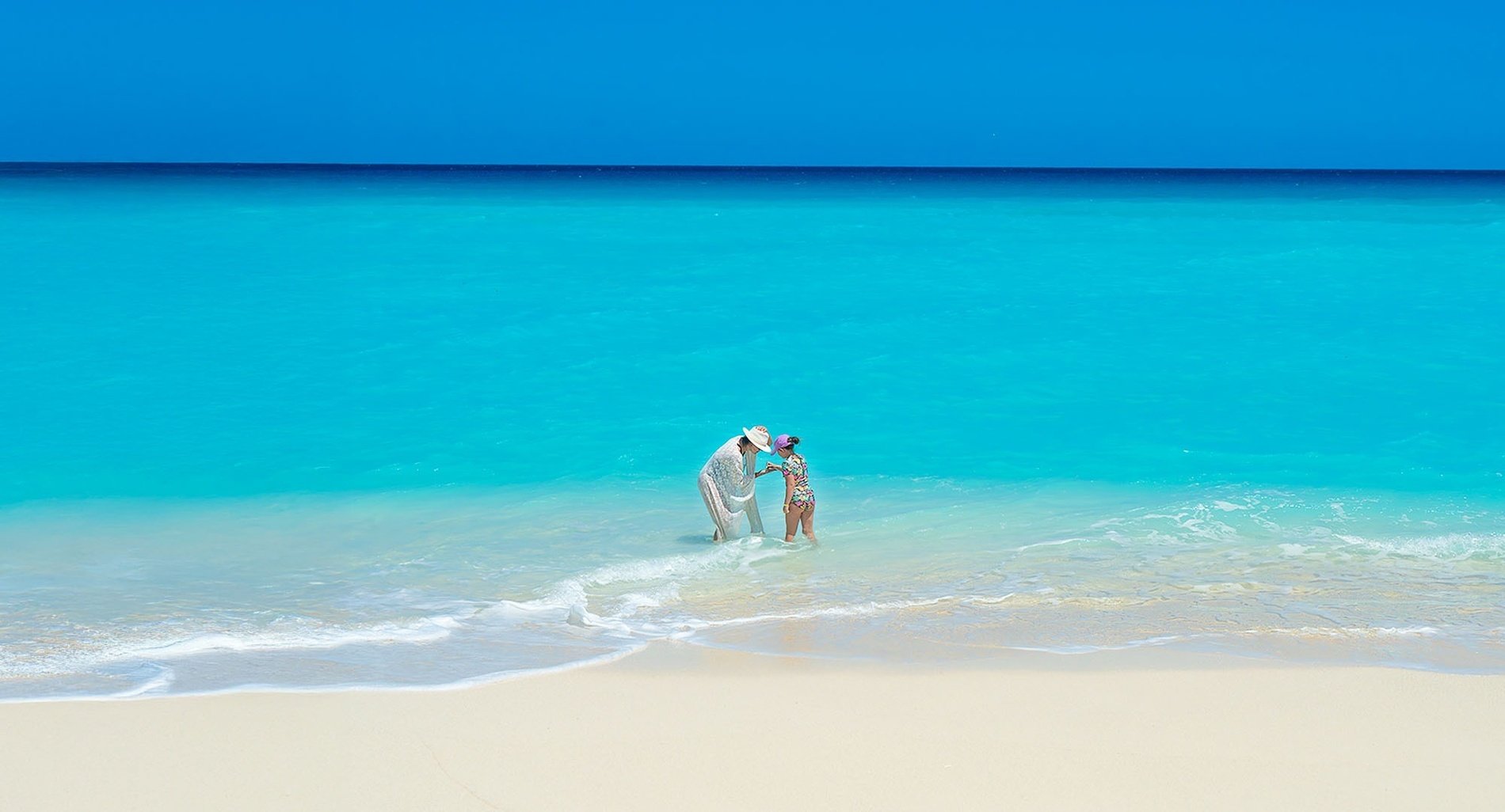 a man and a woman are standing in the water on a beach