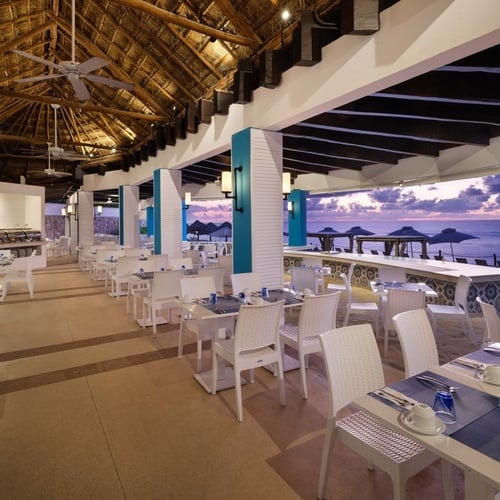 un restaurante lleno de mesas y sillas con vista al océano