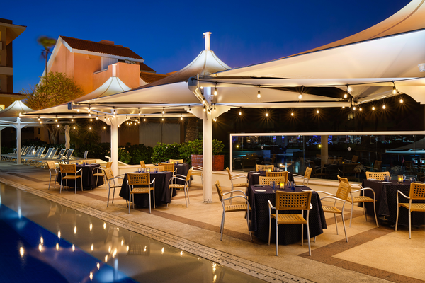 un restaurante al aire libre con mesas y sillas junto a una piscina