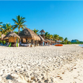 una playa llena de arena blanca y cabañas de paja