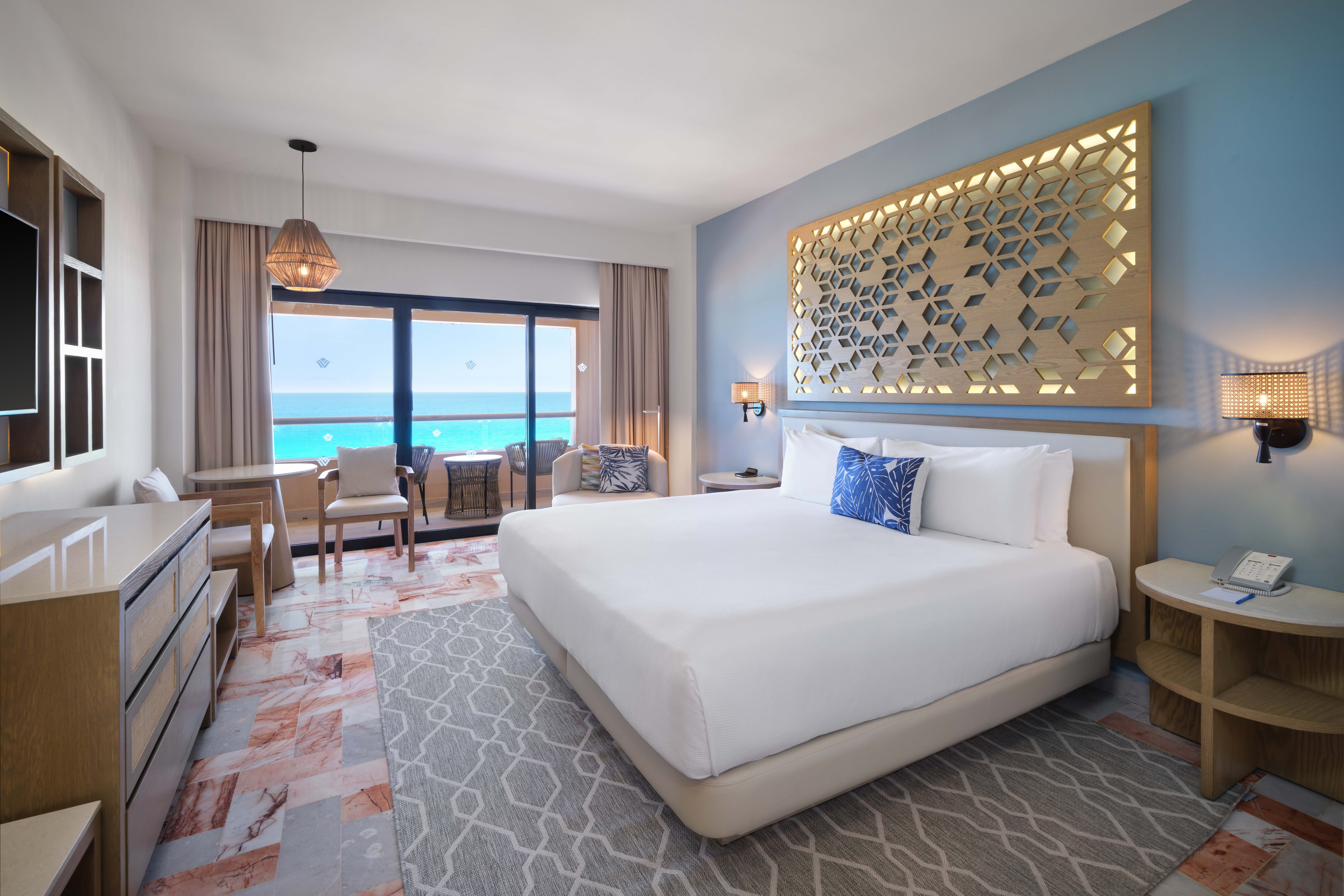 Habitación espaciosa en Wyndham Grand Cancun all inclusive con cama King y área de estar.