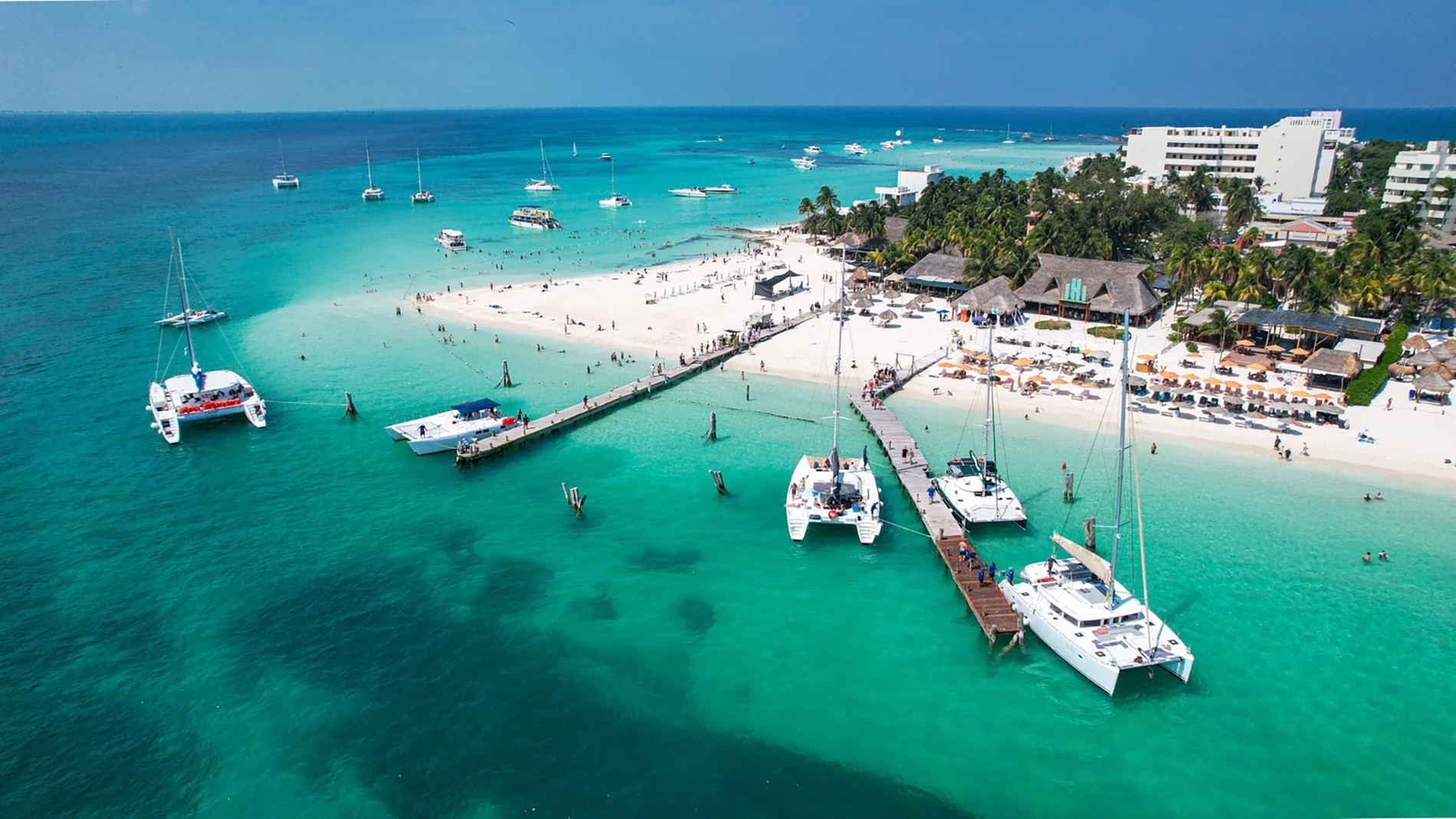 a group of boats are docked at a dock on a beach