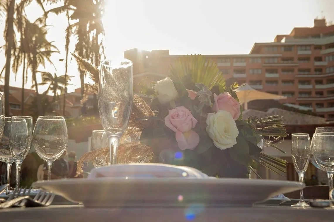 una mesa con platos y copas de vino y un ramo de flores