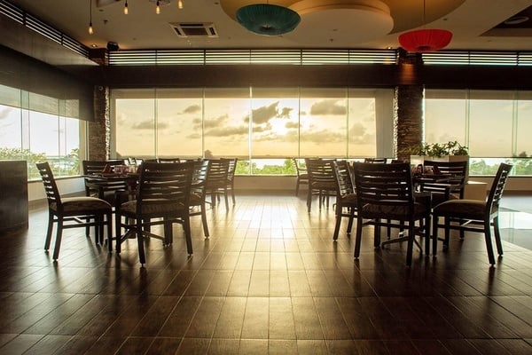 un restaurante vacío con mesas y sillas frente a una ventana al atardecer