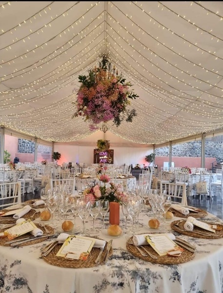 una habitación llena de mesas y sillas con un arreglo floral colgando del techo