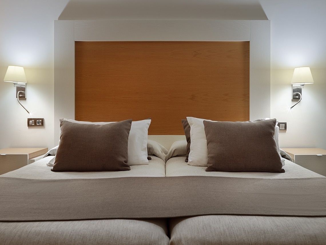 ein Bett mit braunen und weißen Kissen darauf